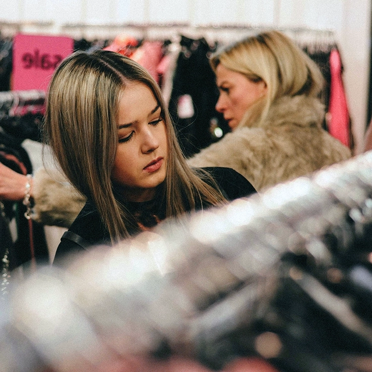 a lady finding the perfect outfit in on a consignment rack